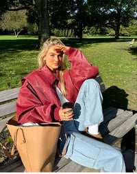 Veste en cuir oversize rouge, manches amples et col ouvert, surpiqûres ton clair.