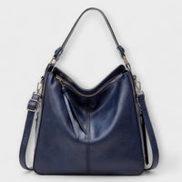 Grand sac hobo bleu en cuir, anse et bandoulière réglables, fermeture zippée.