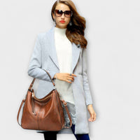 Grand sac hobo marron, porté en bandoulière, avec poche zippée et anses.