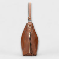 Sac hobo marron porté main avec bandoulière, breloque et zip sur le devant.