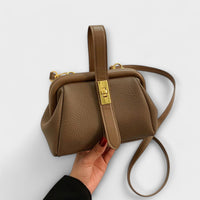 Sac rétro en cuir grainé kaki, bandoulière longue et fermeture centrale à plaque dorée.