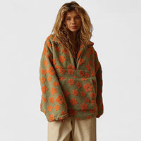 Pull demi-zip à fleurs orange sur fond vert, col montant, manches longues.