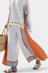 Pantalon ample blanc avec bordures rayées orange et bleues sur la jambe