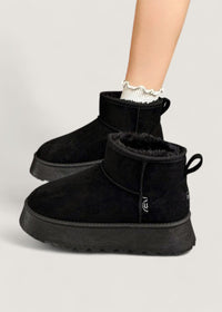 Bottes d’hiver noires, fourrure intérieure visible et semelle crantée épaisse.