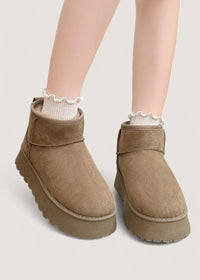 Bottes d’hiver brunes portées avec chaussettes blanches, semelle crantée épaisse.