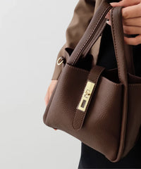 Sac à main en cuir texturé marron, détail de la fermeture et des anneaux de bandoulière