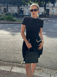 Robe courte noire à manches courtes, ornements pailletés sur la ceinture et les poches