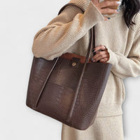 Sac à bandoulière vintage en cuir texturé marron, fermeture boutonnée et lanières larges.