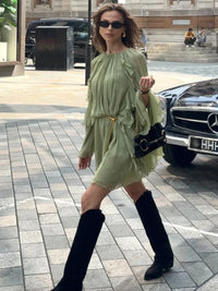 Robe courte vert clair à volants superposés, manches évasées, ceinture dorée.