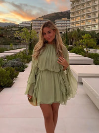 Robe courte fluide vert clair à volants superposés, encolure ronde, vue de face.