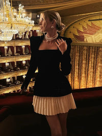 Robe noire à encolure carrée et jupe plissée blanche, détail perles au décolleté