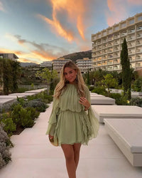 Robe courte fluide vert clair à volants superposés, vue de face.