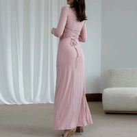 Robe longue rose poudré à manches longues, encolure ronde, couture froncée avec liens à la taille.