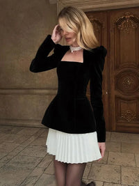 Robe noire ajustée manches longues et jupe courte plissée blanche, empiècements