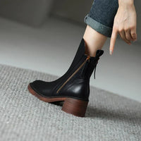 Bottines élégantes Blythe noires portées : talon carré brun et zip latéral.