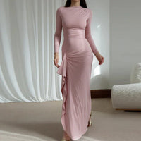 Robe longue rose poudré près du corps, manches longues, encolure ronde, drapé au devant.