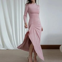 Robe longue rose poudré, manches longues, encolure ronde, drapé en voile avec fente latérale.