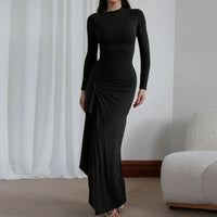 Robe longue noire ajustée, manches longues, encolure ronde, fronces drapées sur le côté.