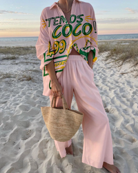 Ensemble deux pièces rose poudré à motif texte « O que », haut col V, pantalon ample.
