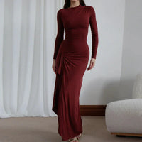 Robe longue rouge bordeaux ajustée, manches longues, encolure ronde, drapé au niveau de la hanche.