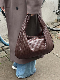Sac cabas tressé marron foncé, anses tressées, texture tissée régulière.