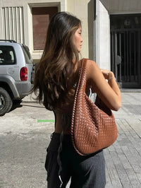 Sac cabas tressé marron, anses tressées, grande ouverture en forme de demi-lune.