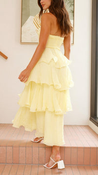 Robe longue jaune à volants superposés, vue de profil, encolure bandeau et jupe à étages.