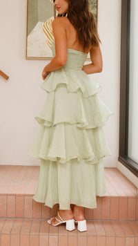 Robe longue vert clair à volants superposés, vue de profil, encolure bandeau et jupe en couches.