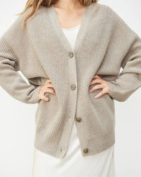 Gilet cocon beige clair en maille côtelée, col V et boutons, coupe ample et manches longues.