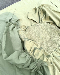 Détail robe midi vert clair : tissu froncé à la taille, manches bouffantes et encolure carrée