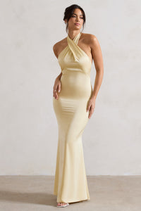 Robe longue satinée jaune pâle, encolure halter, silhouette près du corps, fente.