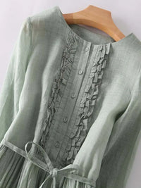 Robe en lin vert clair, encolure boutonnée, volants décoratifs et lien à la taille.