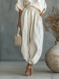 Ensemble deux pièces blanc avec top décolleté asymétrique et pantalon large plissé