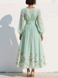 Robe midi vert clair fleurie vue de dos, manches longues, taille froncée et jupe évasée.