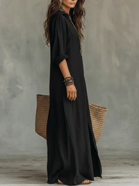 Robe longue noire décontractée à col, vue de profil, manches retroussées et fente.
