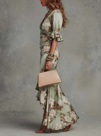 Robe longue asymétrique vert clair à fleurs, manches volantées, fente sur le côté.