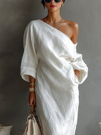 Robe longue blanche fluide, drapé asymétrique une épaule, manches trois-quarts.