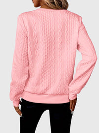 Pull zippé torsadé rose au dos, motif torsades verticales, manches longues.