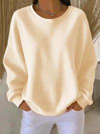 Sweat minimaliste beige clair en tissu texturé, encolure ronde, manches longues amples.