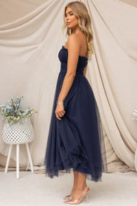 Robe longue Aera en tulle bleu nuit, buste bandeau froncé et jupe ample superposée.