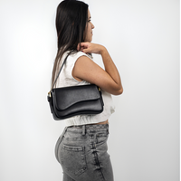 Sac porté épaule noir en cuir, rabat avant, bandoulière et fermoirs dorés.