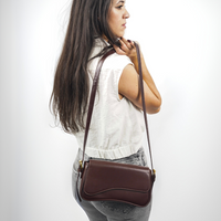 Sac porté épaule en cuir bordeaux avec rabat, surpiqûres contrastées et attaches métalliques dorées.