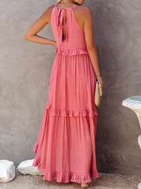 Robe longue rose corail au dos, encolure avec liens, volants étagés sur la silhouette