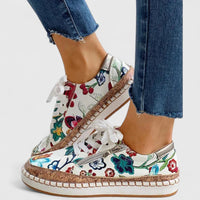 Chaussures orthopédiques à lacets blancs, tige blanche fleurs multicolores, semelle beige.
