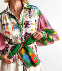 Robe longue imprimée, col boutonné, mains tenant le ruban vert noué à la taille.