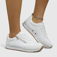 Chaussures orthopédiques blanches à lacets et fermeture éclair, semelle marron.