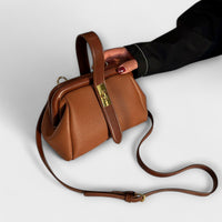 Sac rétro en cuir grainé brun foncé, poignée supérieure et bandoulière avec fermoir doré.