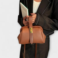 Sac rétro en cuir grainé caramel, bandoulière fine et fermeture centrale à plaque dorée.