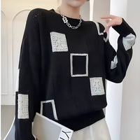 Pull noir en maille avec carrés ajourés blancs et coutures contrastées, col rond.
