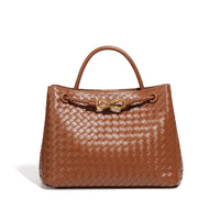 Sac cabas tressé brun, anse rigide et fermoir décoratif doré.